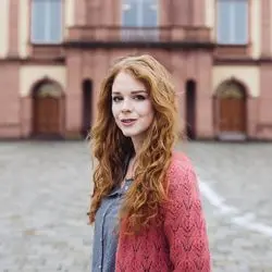 Person Juliane Koch mit roten, langen Haaren auf dem Ehrenhof.
