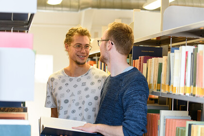 Studierende unterhalten sich in der Bibliothek