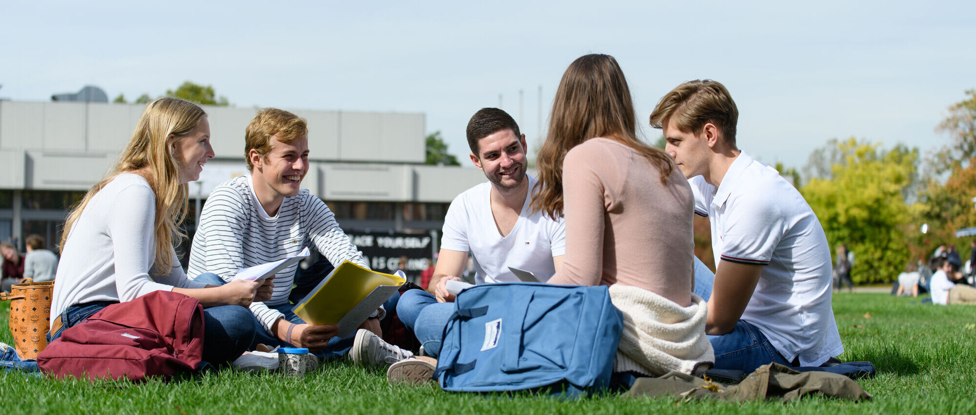 Lerngruppe auf der Mensawiese Eine Gruppe fünf Studierender sitzen mit Lernmaterialien in der Hand auf der Mensawiese.