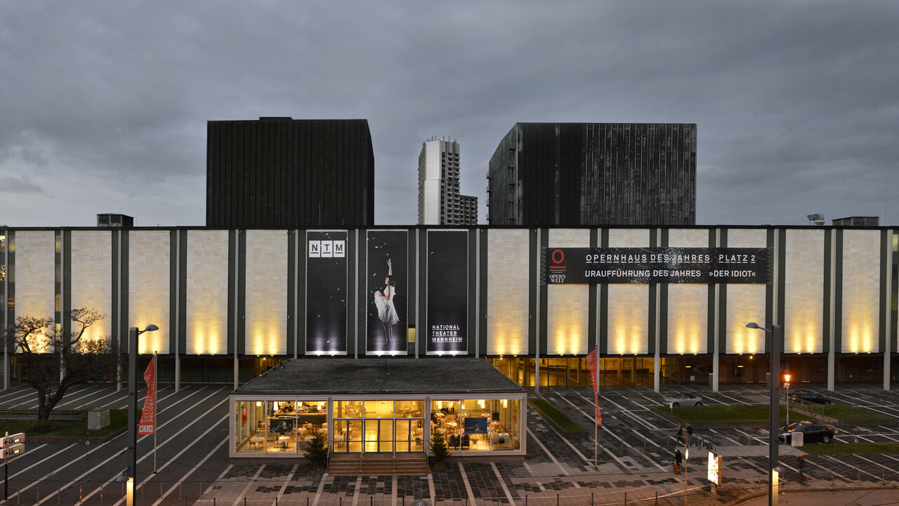 Die Fassade eines Theaterhauses leuchtet in der Dunkelheit.