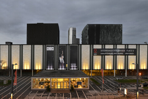 Die Fassade eines Theaterhauses leuchtet in der Dunkelheit.
