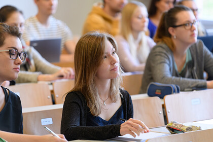 Zuhörerschaft im Lehrsaal, im Vordergrund sind zwei weibliche Studierende zu sehen