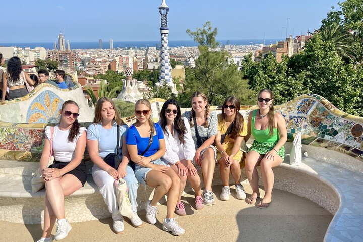 Studierende mit ihrer Katalanischlektorin bei einem Besuch im Parc Güell im Barcelona. Im Hintergrund ist die Stadt Barcelona zu erkennen.  