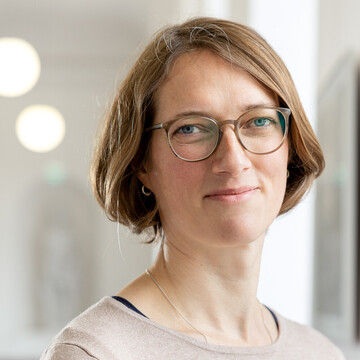 Astrid Lembke hat kurze braune Haare. Sie trägt eine Brille und ein beiges Oberteil.