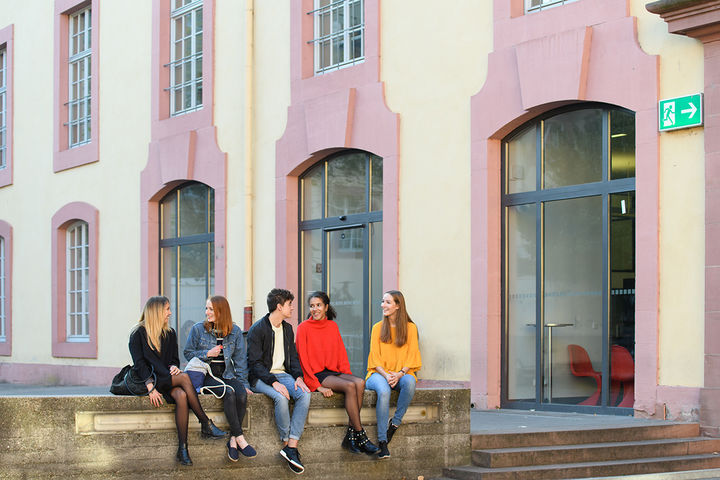 Fünf Studierende auf einer Mauer vor der Schneckenhof-Bibliothek.