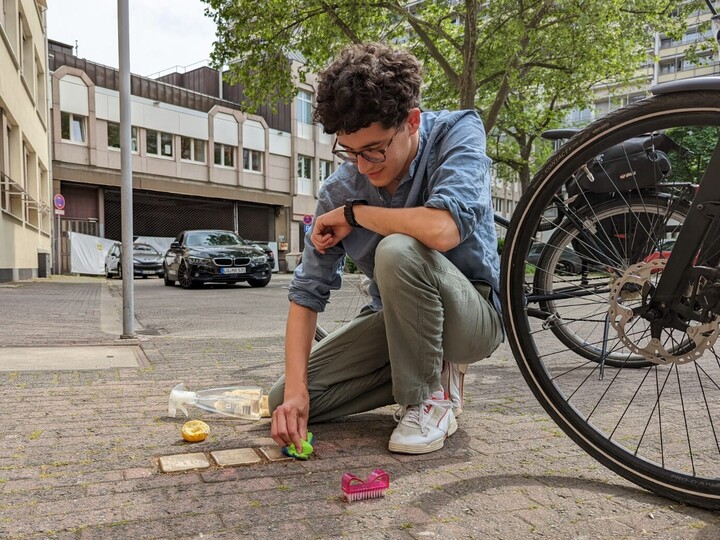 Geschichtsstudent Jonathan Trautmann beim Reinigen von Stolpersteinen in der Ludwigshafener Innenstadt. Eine Person reinigt einen Stolperstein.