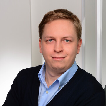 Maximilian Phlipps hat kurze blonde Haare. Er trägt ein hellblaues Hemd und ein schwarzes Jackett.