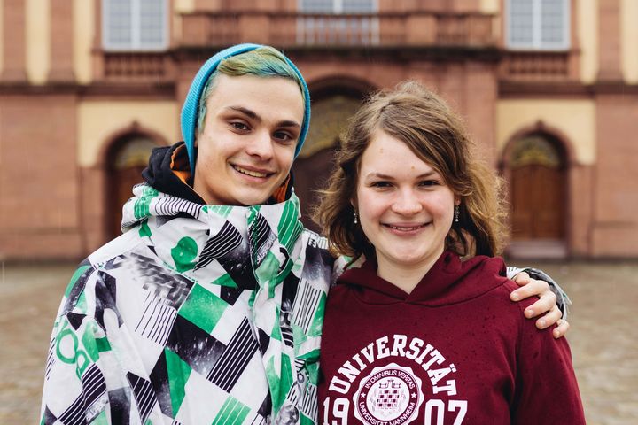 Zwei Studierende Arm in Arm vor dem Mannheimer Schloss.