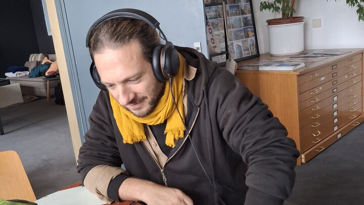 Ein Mann mit Kopfhörern sitzt an einem Tisch.