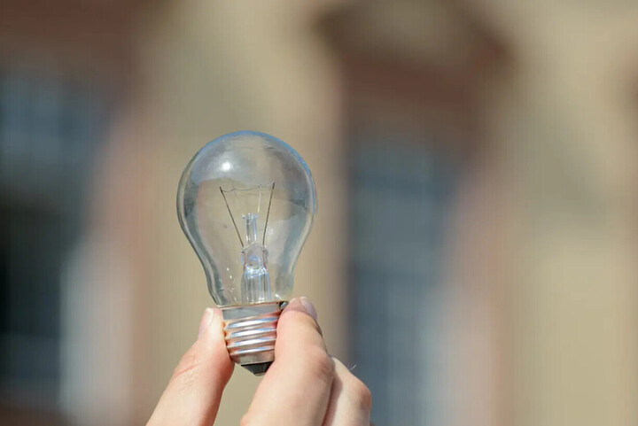 Glühbirne, welche von einer Hand gehalten wird