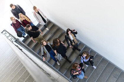 Gruppe Studierender geht eine Treppe im Schloss herunter 