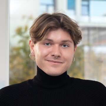 Nico Stab in Frontalansicht, er hat braune Haare und trägt einen schwarzem Rollkragen 