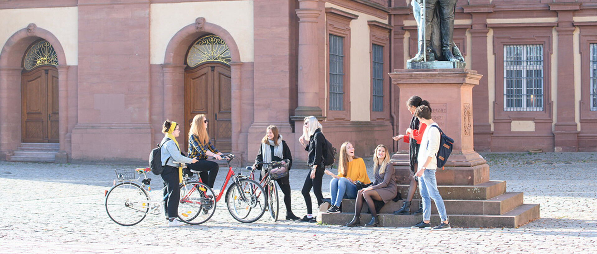 Studierende vor einer Statue am Mannheimer Schloss.