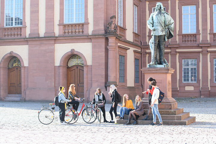 Studierende an einer Statue vor dem Mannheimer Schloss.