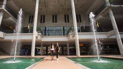 Zwei Studentinnen laufen aus dem Eingang der Mahidol University in Thailand.