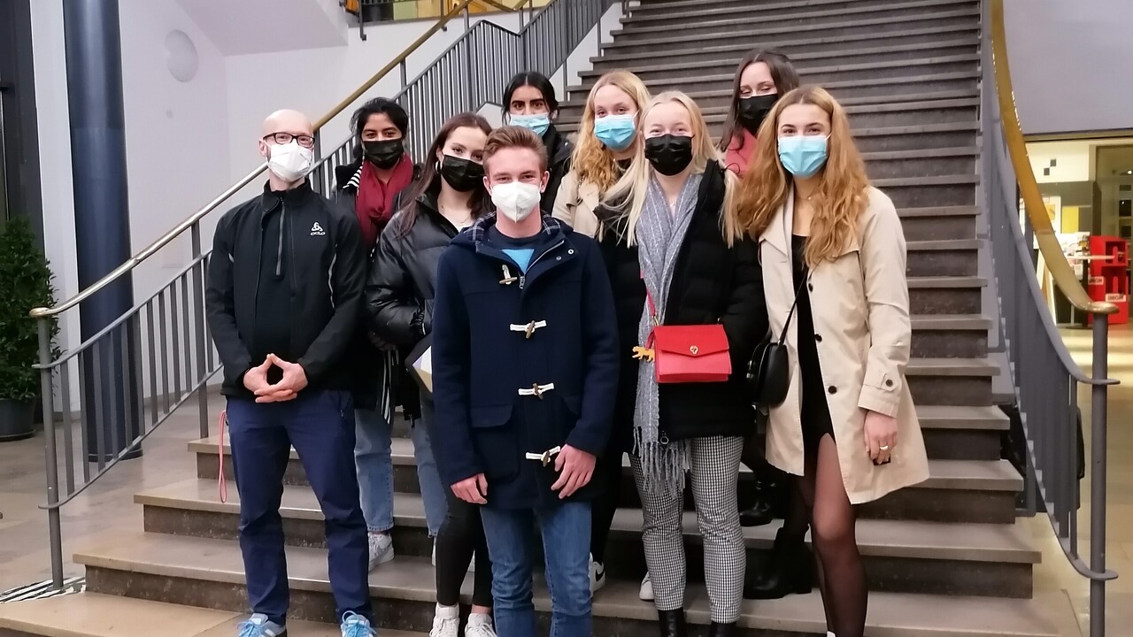 9 junge Menschen mit herbstlicher Kleidung und Corona-Atemschutzmasken auf einem Treppenaufgang. Es handelt sich um Schüler*innen aus dem Philosophiekurs der Jahrgangsstufe 12 im Jahr 2021 des Alber-Einstein-Gymnasiums in Frankenthal.