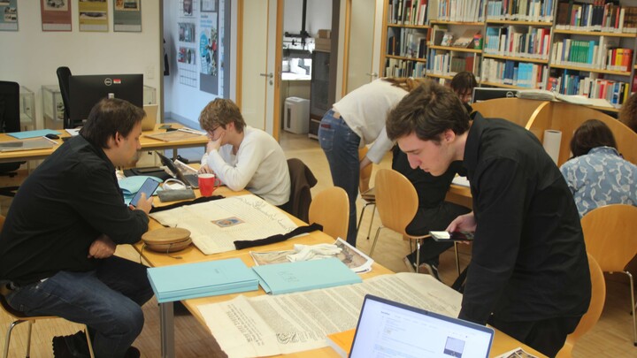Sieben Personen in einem Lesesaal sind in die Lektüre von Originalquellen vertieft