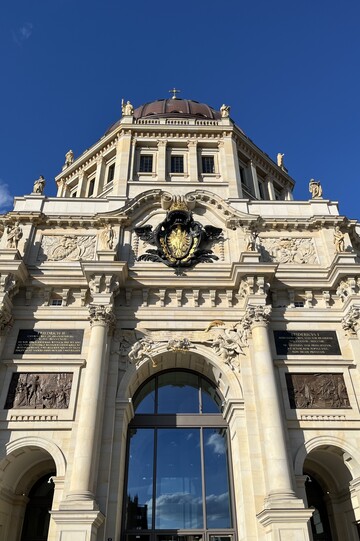 Der Haupteingang des Humboldt Forums im ehemaligen Berliner Schloss von unten fotografiert vor blauem Himmel. 