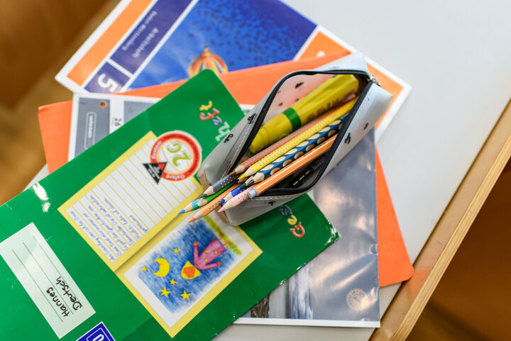 Schulhefte und Schlampermäppchen mit Buntstiften.