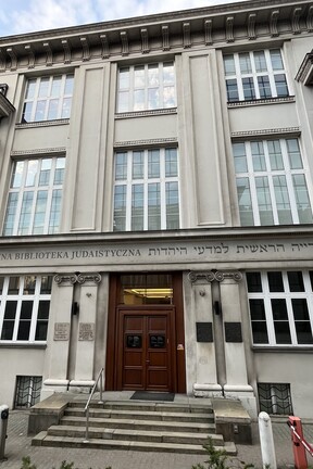 Die Fassade des Jüdischen Historischen Instituts (Żydowski Instytut Historyczny, kurz ŻIH) in Warschau. Ein dreistöckiges Bauwerk mit großen Fenstern, in der Mitte ein hölzernes Eingangsportal mit Treppenaufgang. 