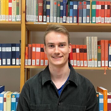 Junger Mann mit Rücken zum Bücherregal