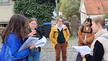 4 Personen hören einer erklärenden Person zu