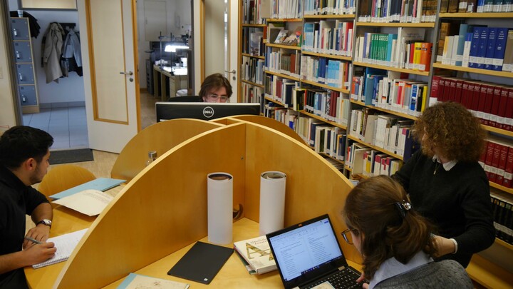 Zwei Frauen und zwei Männer an einem runden Tisch in einem Lesesaal