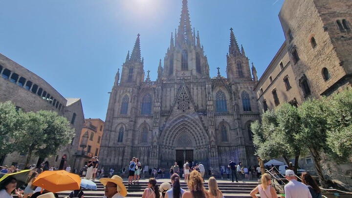 Studierende bestaunen die Kathedrale von Barcelona. Sie stehen am Fuße einer Treppe. 