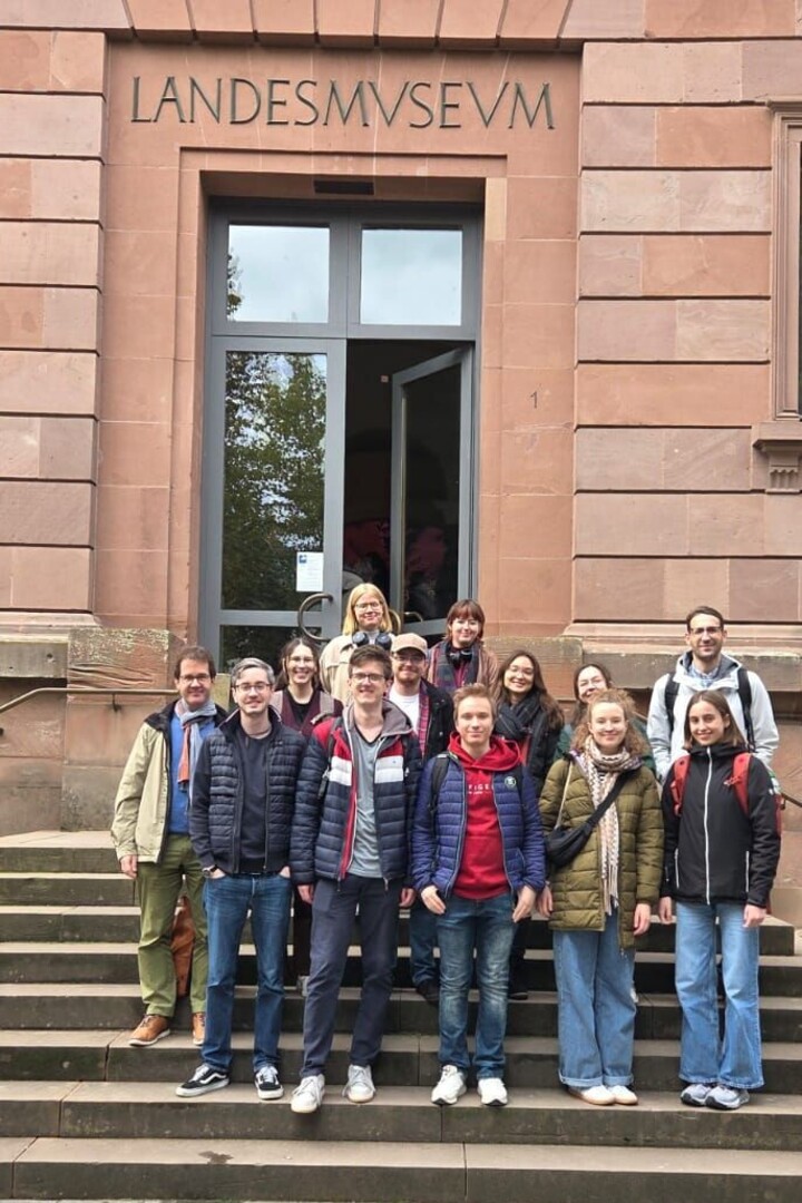 Die Teilnehmenden der Exkursion stehen auf der Treppe vor dem Haupteingang des Rheinischen Landesmuseums Trier. 