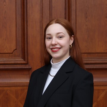 Felicia Metternich vor dem Portal des Mannheimer Schlosses. Sie trägt einen schwarzen Blaser und hat lange, rote Haare.