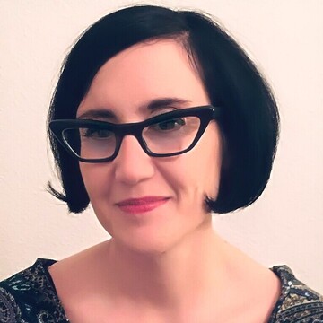 María José Carrión hat schwarze, kinnlange Haare. Sie trägt eine schwarzumrandete Brille.