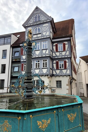 Schmiedeeiserner Brunnen vor einem Fachwerkhaus