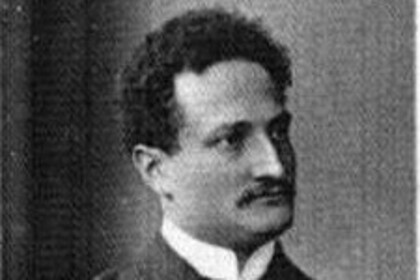 Ludwig Frank in dunklem Anzug und mit hellem Hemd. Er trägt kurzes dunkles Haar und einen Schnurrbart.