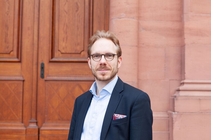 Dr. Martin Brecher. Er trägt ein dunkelblaues Sakko und steht im Ehrenhof des Mannheimer Schlosses.