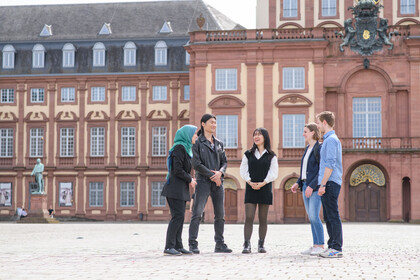 Fünf Persone stehen auf dem Ehrenhof des Schlosses und reden miteinander.