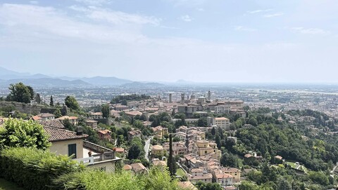 Panoramablick auf die Stadt Bergamo mit historischen Gebäuden und grünen Hügeln im Vordergrund
