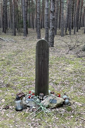 Gedenkstein am Gedenkort Zbereźe in der Nähe des ehemaligen Vernichtungslagers Sobibor: Eine hölzerne Mazewa auf einer Lichtung im Wald, darum herum andere (Gedenk-)Steine, Kerzen und Blumen. Auf dem Holz steht: „In Göttlicher Erinnerung ruhen hier Juden, die im Holocaust ermordet worden.“ in hebräischer Sprache steht hinzugefügt: „Mögen ihre Seelen zu Gott kommen“.