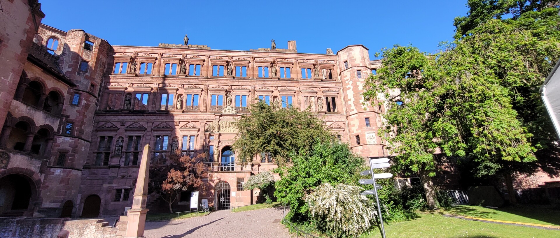 Ansicht des aus rotem Sandstein gebauten Ottheinrich-Baues mit zahlreichen Statuen an der Fassade vor blauem Himmel