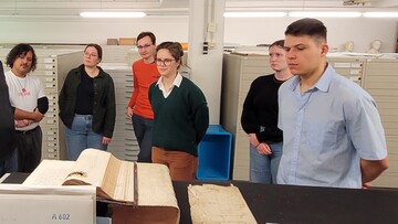 6 Personen in einem Depotraum eines Archivs mit Archivalien